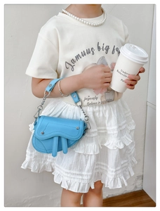 Détail du sac selle bleu clair en cuir grainé avec poignée en chaîne argentée