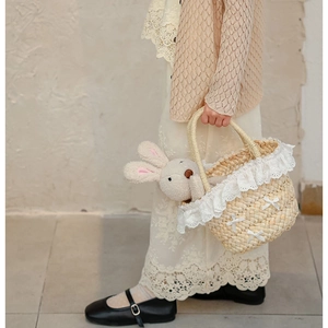 Détail du panier en paille tressée pour enfants avec dentelle blanche et petits nœuds