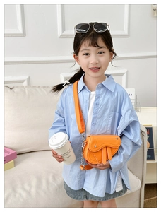 Détail du mini sac selle orange vif avec large bandoulière et chaîne pour filles
