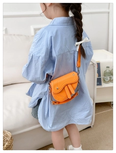 Détail du sac selle orange pour enfant en cuir grainé avec bandoulière chaîne argentée