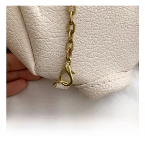Détail du fermoir mousqueton en métal doré et de la bandoulière en cuir beige texturé