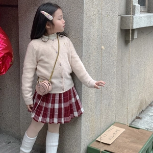 Toddler girl in beige cardigan and red plaid skirt carrying a pink mini round chain purse