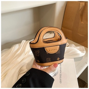 Detail of mini PU leather bucket bag with bear print and caramel trim in hand