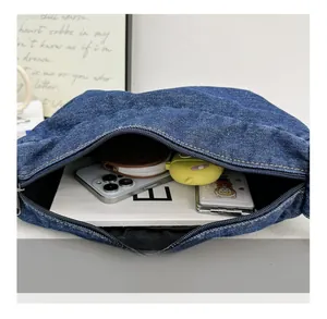 Spacious interior of blue denim tote showing storage for phone, notebook and earbuds