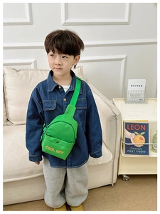 Detail der grünen Nylon-Kindertasche mit orangefarbenem COOL BOY Aufdruck und Gurt
