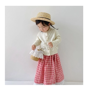 Detail of child wearing summer straw bucket bag with lace edge and white knit cardigan