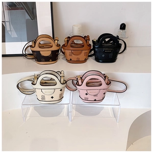 Detail view of mini cartoon bear bucket bag with textured faux leather and metal brand logo