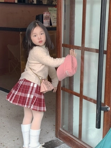 Tenue enfant avec pull beige, jupe à carreaux et petit sac à bandoulière rose