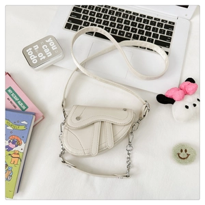 Vue détaillée du sac selle blanc crème avec texture cuir grainé et chaîne argentée
