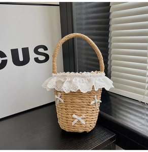 Vue détaillée du sac seau en paille avec bordure en dentelle et nœuds décoratifs
