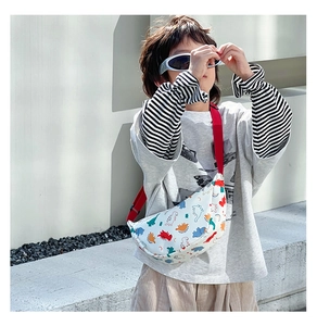 Outdoor shot of a child wearing a white crescent nylon bag with colorful dinosaur prints