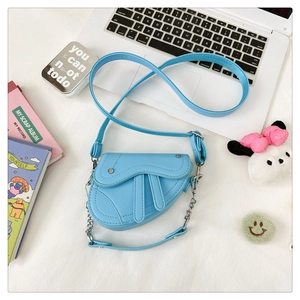Gros plan du sac selle bleu clair avec bandoulière cuir et détail de chaîne