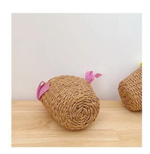 Detail of hand-woven straw beach bag featuring a pink and white checkered ribbon bow