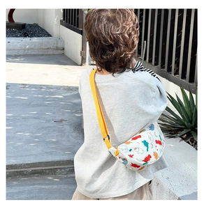 Rear view of a child wearing a white nylon chest bag with colorful cartoon dinosaur prints