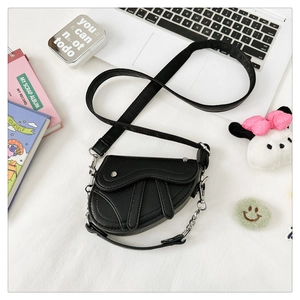 Détail du mini sac selle en cuir grainé noir avec chaîne argentée et bandoulière