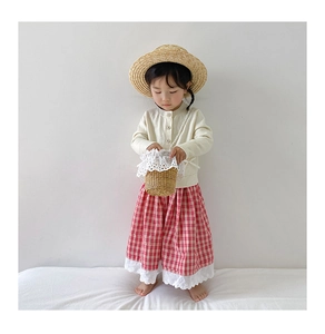 Close-up of a child's woven straw bucket bag featuring elegant white lace floral details
