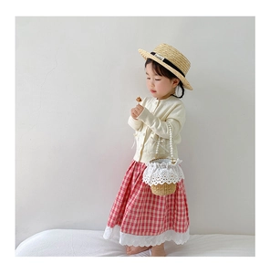 Detail of children's straw bucket bag with elegant pearl handle and lace accents