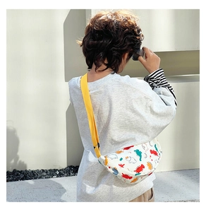 Close-up of kids dinosaur print fanny pack with bright yellow adjustable strap and zipper