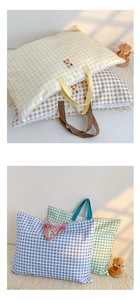 Détail du sac en toile à carreaux montrant les poignées renforcées et la fermeture éclair