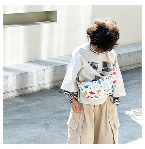 Kid's nylon crossbody bag with colorful dinosaur print worn across chest for daily use