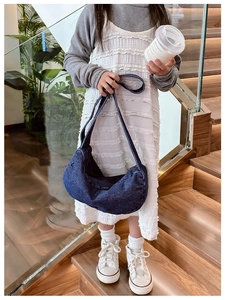 Close-up of children's navy denim hobo bag with wide shoulder strap on a model