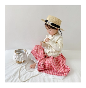 Detail of a handmade straw bucket bag with elegant pearl strap and lace trim for kids