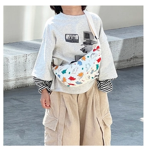 Kids floral dinosaur nylon crossbody bag worn by child showing crescent shape and fit