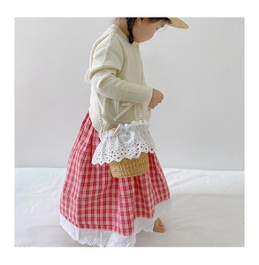 Detail of straw woven bucket bag for kids featuring delicate lace trim and pearl handle