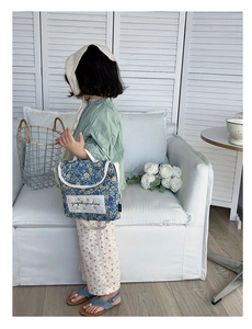 Close-up of children's blue floral handbag with rustic cotton fabric and print detail