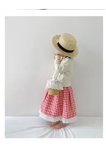 Detail of a kids straw bucket bag with white lace trim and elegant pearl handle