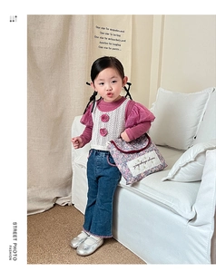 Girl's stylish outfit with floral handbag, crochet vest, and denim flared pants