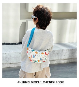 Outdoor shot of a child wearing a colorful dinosaur print nylon crossbody bag with blue strap