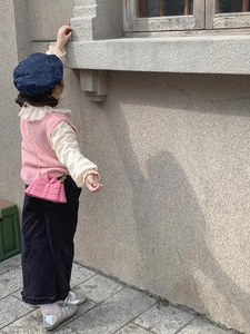 Détail du sac bandoulière rose en forme de veste avec une tenue d'automne en tricot