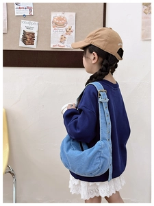 Detail of light blue denim crossbody tote bag with adjustable strap and vintage texture