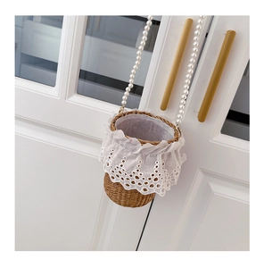 Detail of straw woven bucket bag with elegant white lace trim and pearl strap