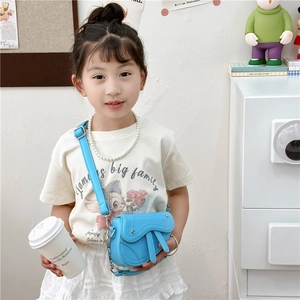 Mini sac selle bleu vif pour filles porté par un mannequin dans un intérieur chaleureux