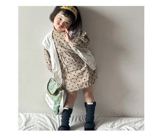 Detail view of quilted white vest and polka dot dress paired with floral crossbody bag