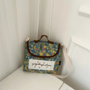 Detail of floral kids crossbody bag with brown handle and adjustable woven shoulder strap