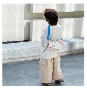 Detail of cute dinosaur print on white canvas kid crossbody bag with blue strap