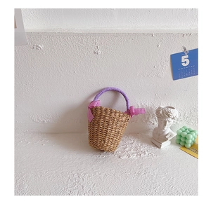 Detail of woven straw bag with purple gingham handles and pink decorative bows