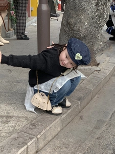 Détail d'un mini sac à bandoulière beige en forme de veste avec chaîne dorée pour enfant