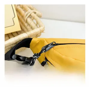 Detail of smooth black zipper and woven puller on yellow nylon kids crossbody bag