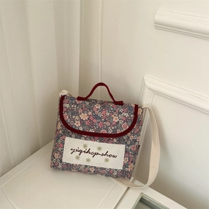 Close-up of floral print kids' crossbody bag with white fabric patch and woven strap