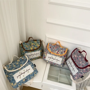 Detail of floral cotton crossbody bags in four colors on a white shelf display