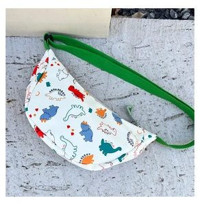 Detail of kids nylon waist bag with colorful dinosaur prints and green adjustable strap