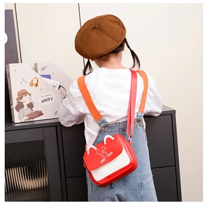 Détail du sac bandoulière rouge enfant avec oreilles d'ours porté par un enfant en salopette