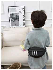Kid wearing a black nylon waist bag with three white stripes and adjustable strap