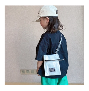 Détail du petit sac à bandoulière blanc pour enfant avec sangle à damier et patch tendance