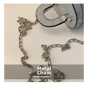 Gros plan détaillé de la chaîne en métal brillant sur un mini sac seau à paillettes argent