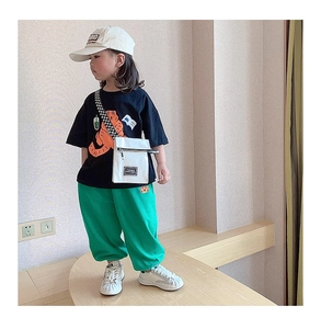 Détail d'une tenue décontractée enfant avec t-shirt noir imprimé et pantalon de jogging vert